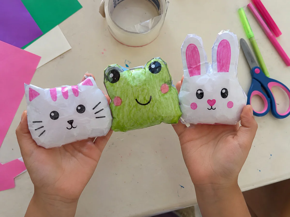 Mãos de uma criança mostrando Paper Squishies de animais